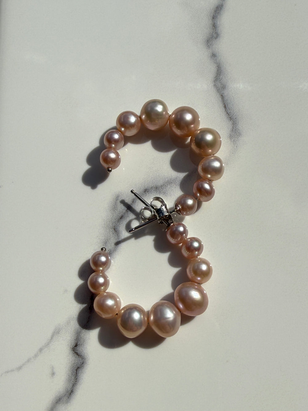 Sterling silver pearl J hoop earrings — worn on ear