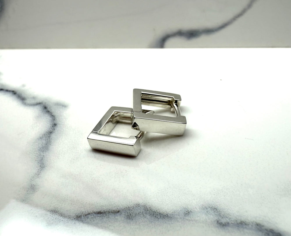 Sterling silver cuboid huggie earrings — worn on ear